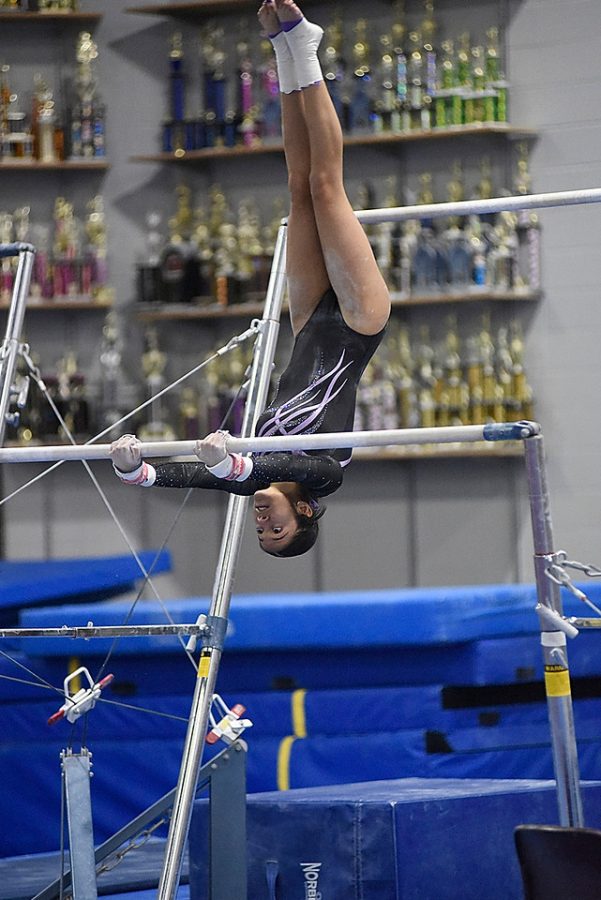 Senior gymnast performs on the uneven parallel bars on Senior Night.