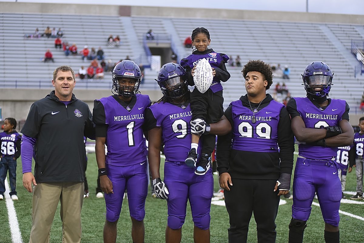 The football teams four captains pose with a Pop Warner player before Friday nights victory over Portage.