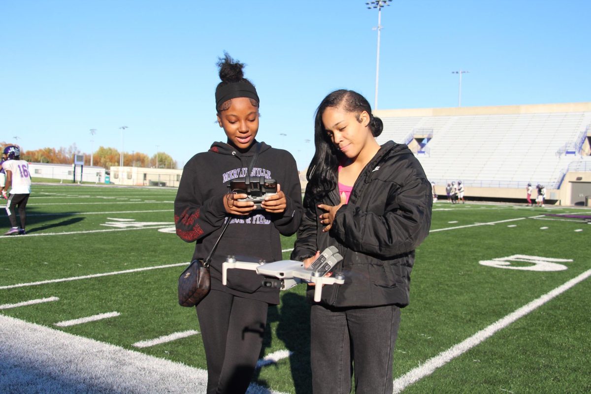 Seniors Nina Marshall and Marley Anderson fly the drone that will record practice for the Pirates football team.